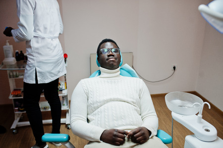African american man patient in dental chair. Dentist office and doctor practice concept.の写真素材