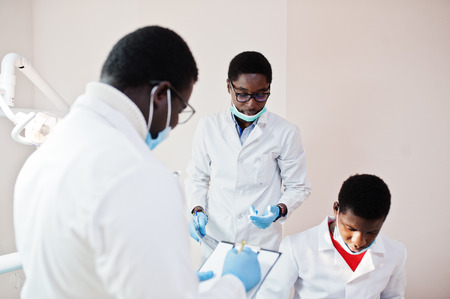 Three african american male doctors working, discussing with colleagues in clinic.の写真素材