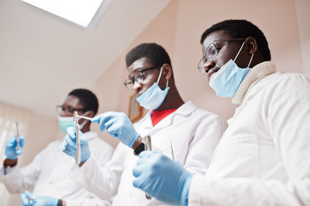 Close uo of three african american male doctors colleagues with tools at hands in clinic.の写真素材