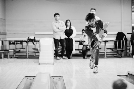South asian man in jeans shirt standing at bowling alley and throw ball.の写真素材