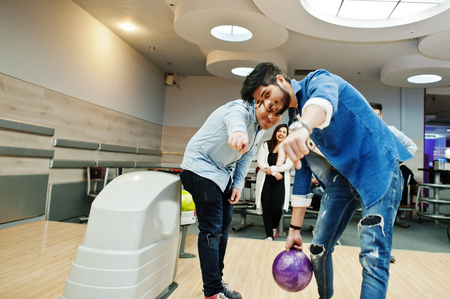 South asian mans in jeans shirt standing at bowling alley with ball on hands and aiming. Guy is preparing for a throw.の写真素材