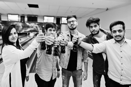 Group of five south asian peoples having rest and fun at bowling club. Clinking cold soda drinks from glass bottles.の写真素材