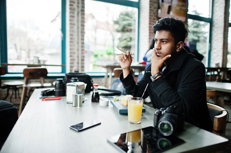 Casual and stylish young asian man with earphones at cafe eating sushi.の写真素材