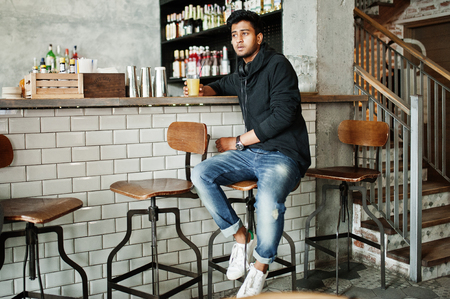 Casual and stylish young asian man with earphones at cafe on bar drinking juice from glass.の写真素材