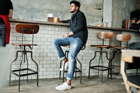 Casual and stylish young asian man with earphones at cafe on bar drinking juice from glass.の写真素材