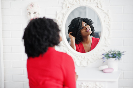 Fashion african american model in red beauty dress, sexy woman posing evening gown and looking at mirror.の写真素材