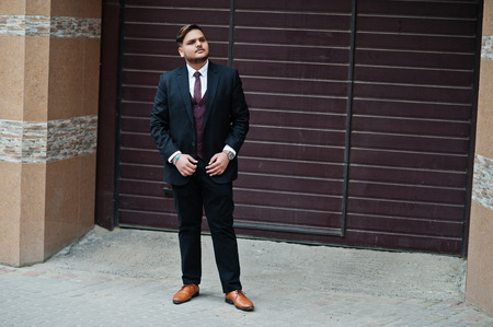 Stylish indian businessman in formal wear standing against brown shutter.の写真素材