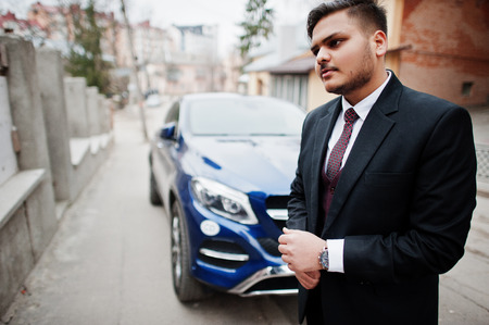 Rich indian diplomat businessman in formal wear standing against business suv car.の写真素材