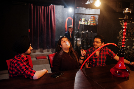 Group of indian friends sitting at lounge bar, smoke hookah and having rest.の写真素材