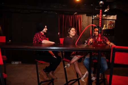 Group of indian friends sitting at lounge bar, smoke hookah and having rest.の写真素材