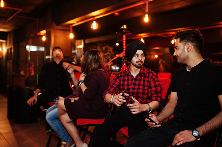 Group of indian friends sitting at lounge bar, smoke hookah and having rest.の写真素材
