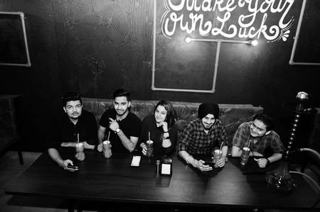 Make your own luck! Group of indian friends having fun and rest at night club, drinking cocktails...