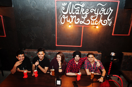 Make your own luck! Group of indian friends having fun and rest at night club, drinking cocktails...