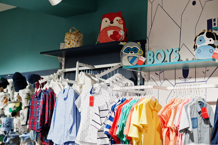Children's bright clothes hang on the display in the baby clothing store. Boys section.の写真素材