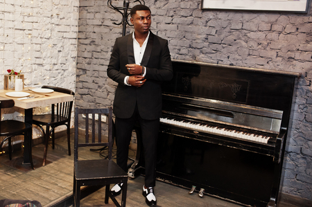 Strong powerful african american man in black suit standing against piano.の写真素材