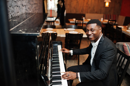 Strong powerful african american man in black suit play piano.の写真素材