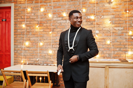 Strong powerful african american man in black suit and turtleneck, afro beads necklace and elephant tusk.の写真素材
