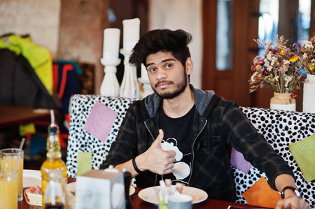 Beard asian man in casual wear sitting indoor cafe, read menu and show thumb up.
