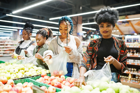 Group of five african womans picking up apples in plastic bags at supermarket.の写真素材