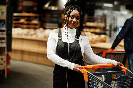 African american woman with shopping cart trolley in the supermarket store.の写真素材