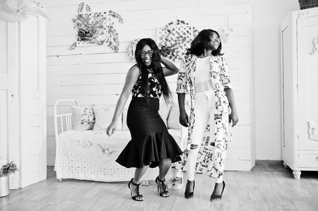 Two african woman friends wear on eyeglasses posed indoor white room. Laughing and having fun together.の写真素材