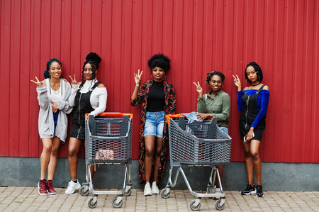 Group of five african american woman with shopping carts having fun together outdoor.の写真素材