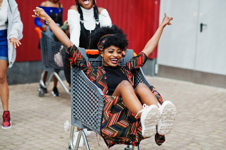 Group of five african american woman with shopping carts having fun together outdoor.