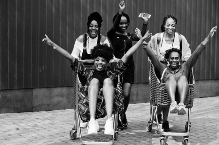 Group of five african american woman with shopping carts having fun together outdoor.の写真素材