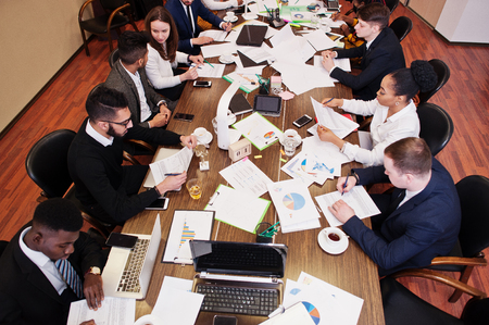 Multiracial business team addressing meeting around boardroom table, working together and write something on papers.の写真素材