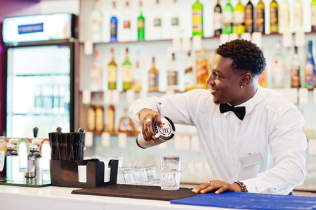 African american bartender at bar with shaker. Alcoholic beverage preparation.の写真素材