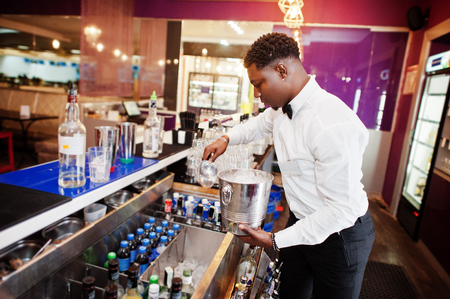 African american bartender at bar with ice bucket. Alcoholic beverage preparation.の写真素材