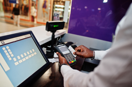 African american bartender at bar uses a credit card terminal on cashier.の写真素材