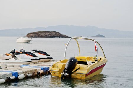 Yellow motor boat with jet ski on a calm blue sea of Bodrum, Turkey.