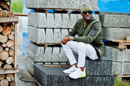 Stylish african american man in hat and sunglasses posed outdoor in rain.