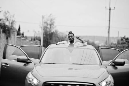 Rich business african woman in silver suv car on sunroof having fun.