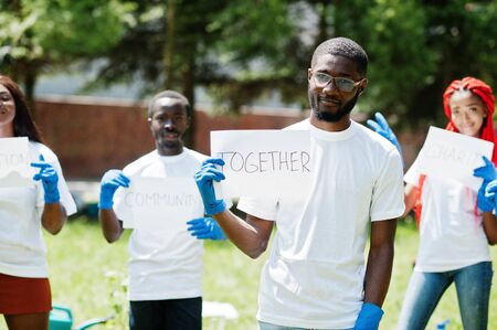 Group of happy african volunteers hold blank board with together sign in park. Africa volunteering, charity, people and ecology concept.の写真素材