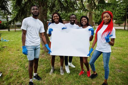 Group of happy african volunteers hold empty blank board in park. Africa volunteering, charity, people and ecology concept. Free space for your text.の写真素材