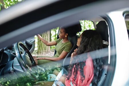 Two african american girls friends having fun in the car.