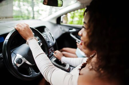 Two african american girls friends having fun in the car.の写真素材