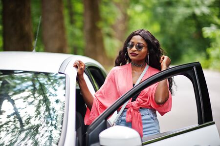 African american woman posed against white car in forest road.の写真素材