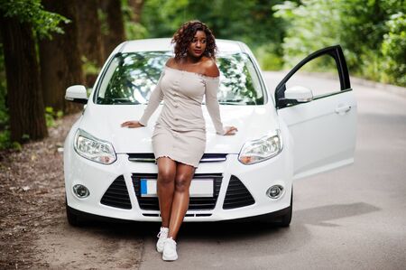African american woman posed against white car in forest road.の写真素材