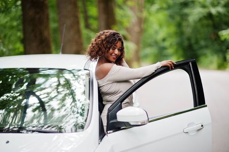 African american woman posed against white car in forest road.の写真素材