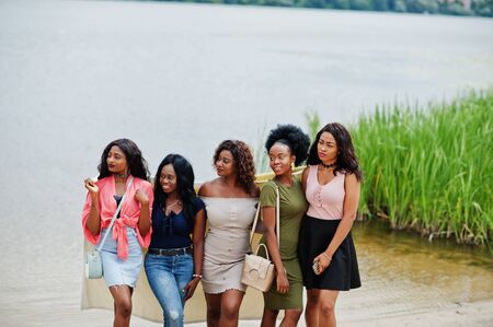 Group of five african american girls standing at sand against lake.の写真素材