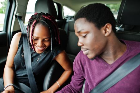 Beautiful young african american couple sitting on the front passenger seats while handsome man...