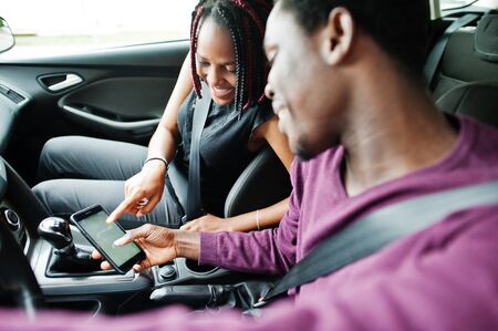 Beautiful young african american couple sitting on the front passenger seats while handsome man...