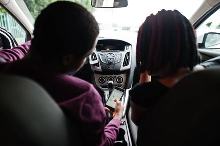 Beautiful young african american couple sitting on the front passenger seats while handsome man...