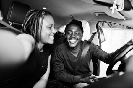 Beautiful young african american couple sitting on the front passenger seats while handsome man...