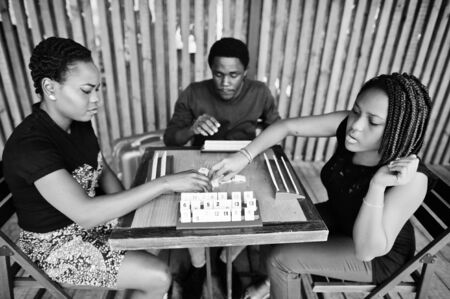 Group of three african american friends play table games.