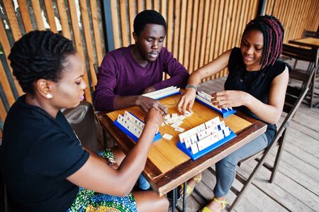 Group of three african american friends play table games.