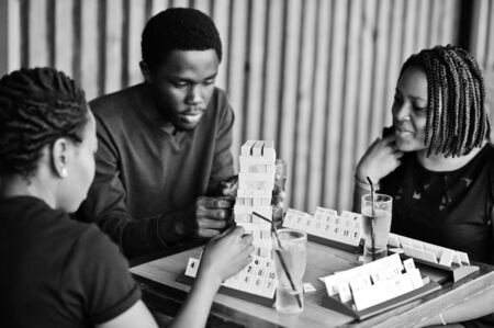 Group of three african american friends play table games.